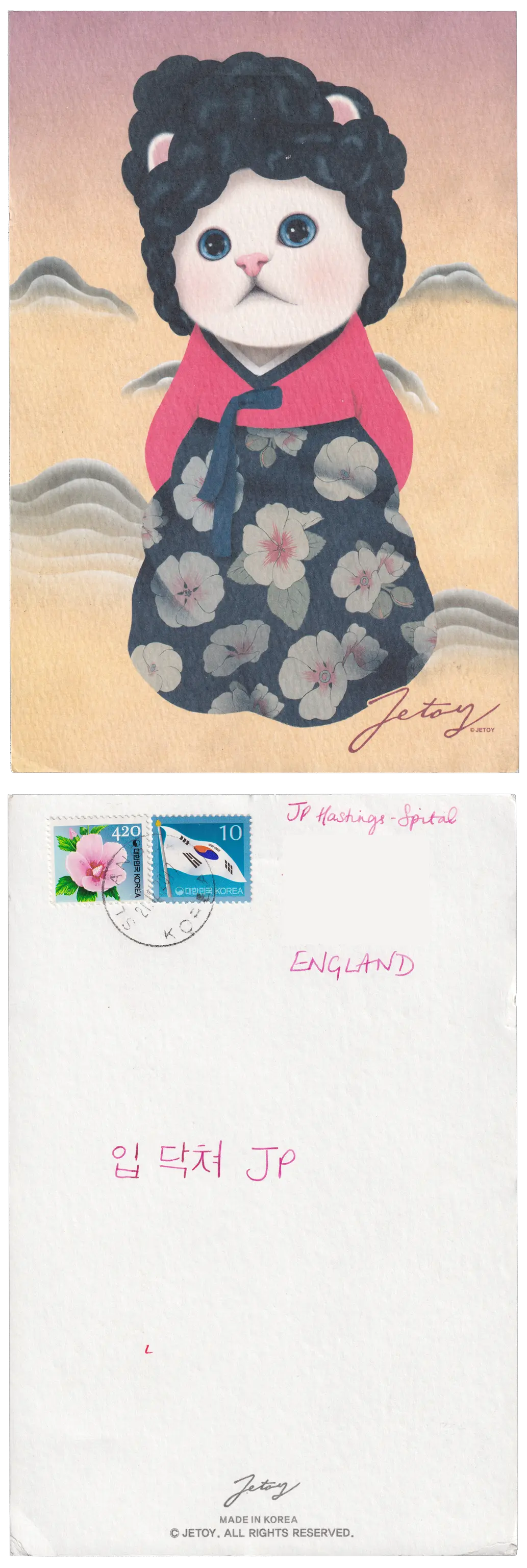 Both sides of a postcard. On the front: A Jetoy branded illustration. A red through red pastel coloured backdrop with simple mountains or clouds. In the foreground a white furred and blue eyed kitten, with a (human-style) head of black hair, is wearing a kimono with white flowers on a blue background. On the back: 입 닥쳐 JP