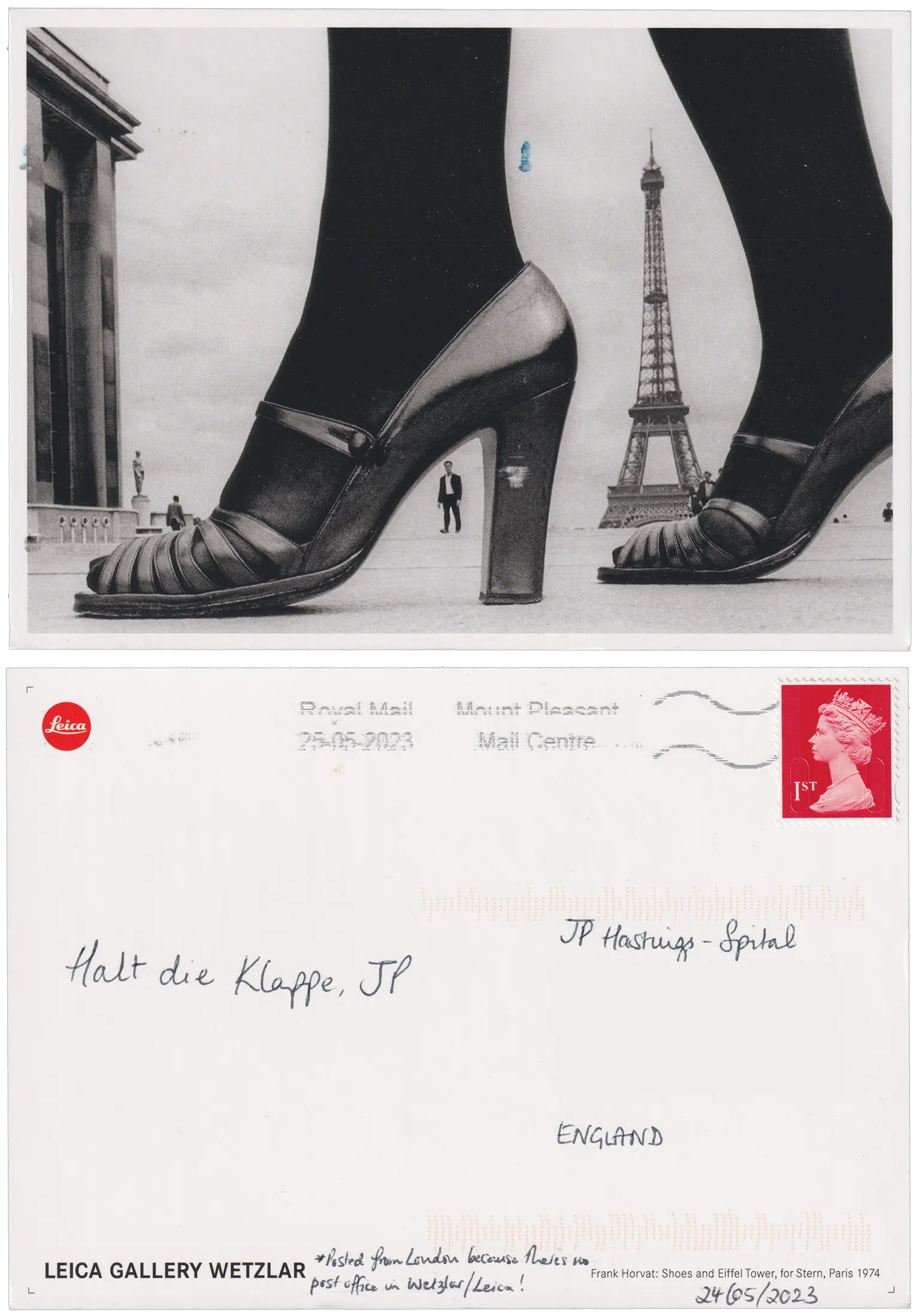 Both sides of a postcard. On the front: A black and white close-up photo of a presumed woman's feet in high-heels and tights with the arch of the heel perfectly framing a distant man in a suit. All next to the Eiffel Tower. On the back: Halt die Klappe, JP