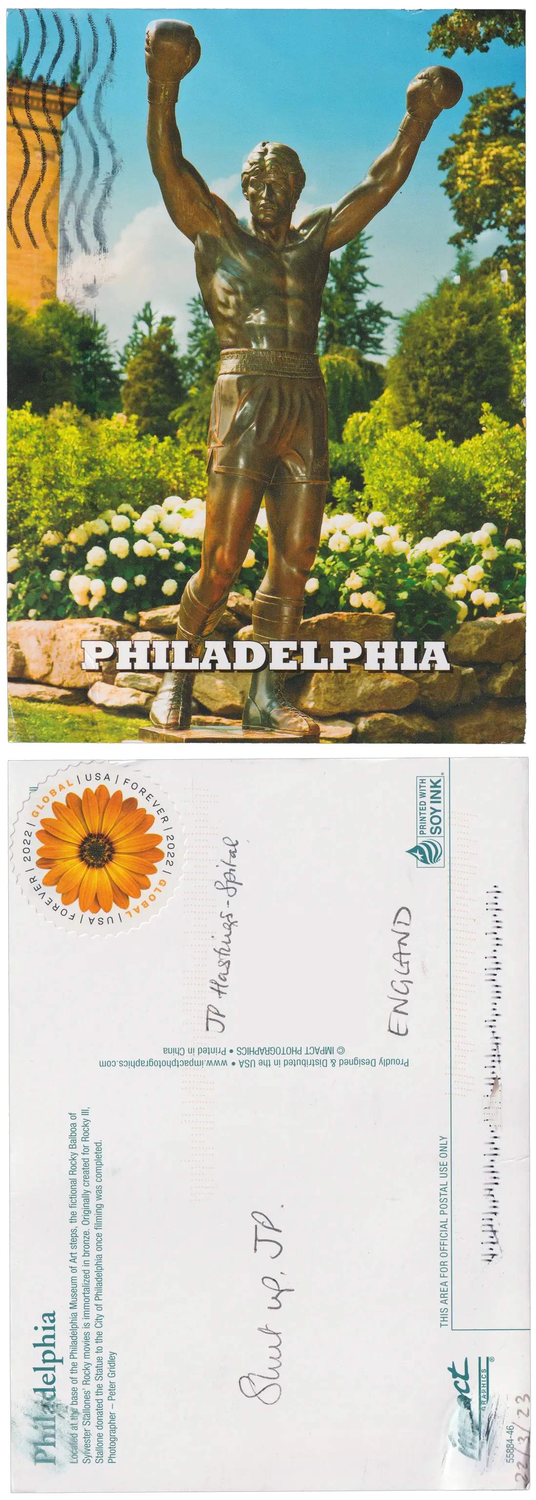 Both sides of a postcard. On the front: A photograph of a bronze statue of Rocky Balboa, a fictional boxer from the Rocky film series, wearing boxing gloves and shorts, with his arms raised in victory. On the back: Shut up, JP.